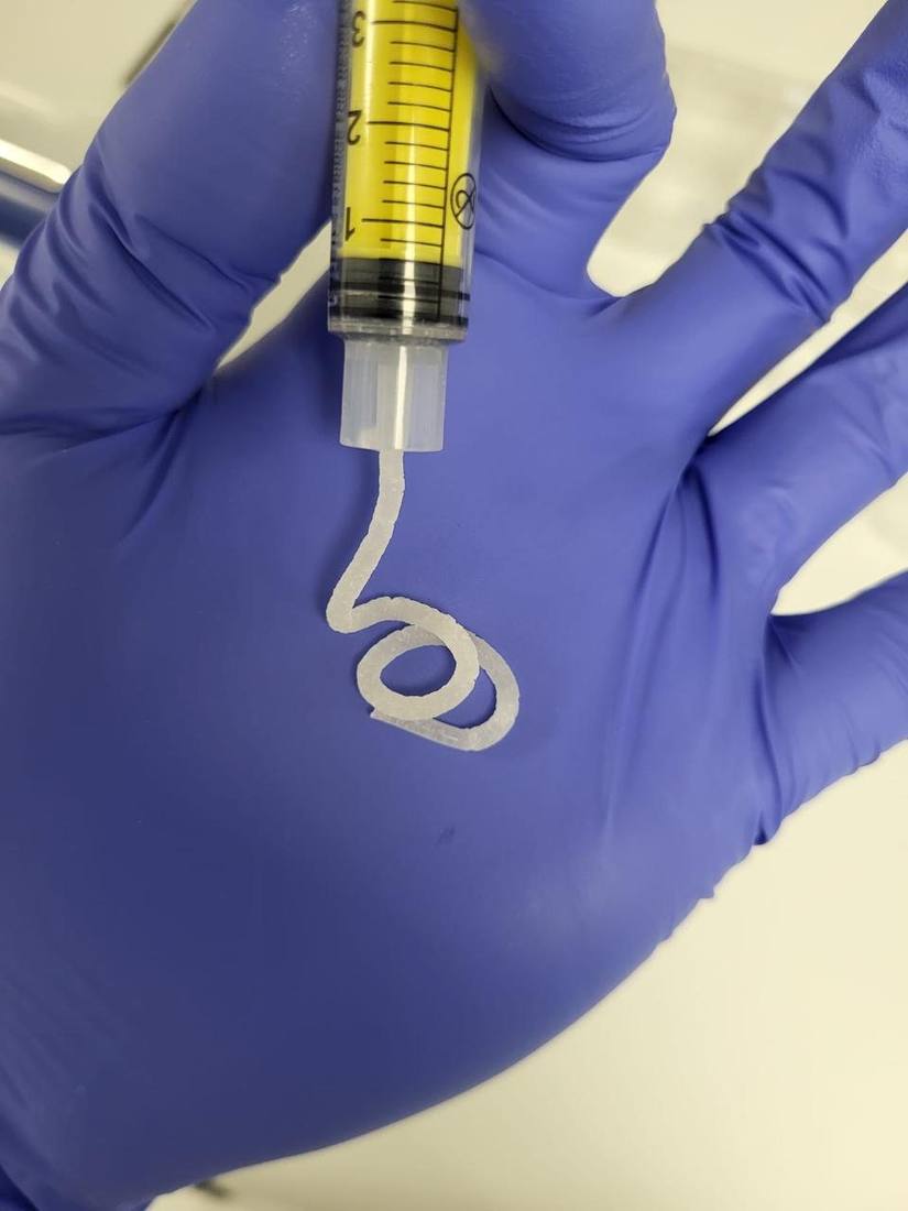 Close-up of biofabricated material from a syringe in a gloved hand